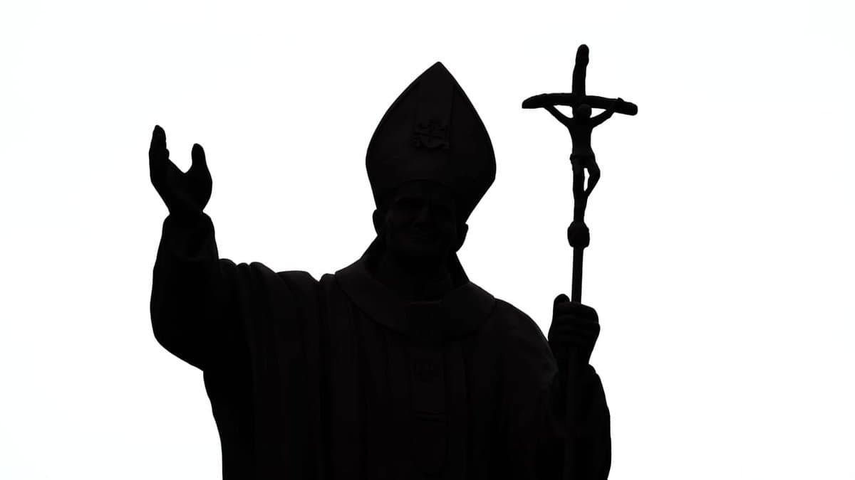 A Catholic priest holding up a cross.