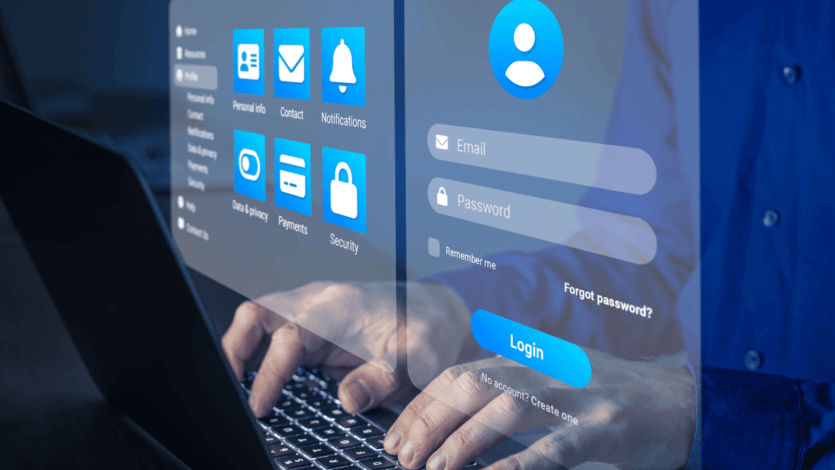 Hands typing at a keyboard in front of a computer screen showing a log-in screen and various icons for data.