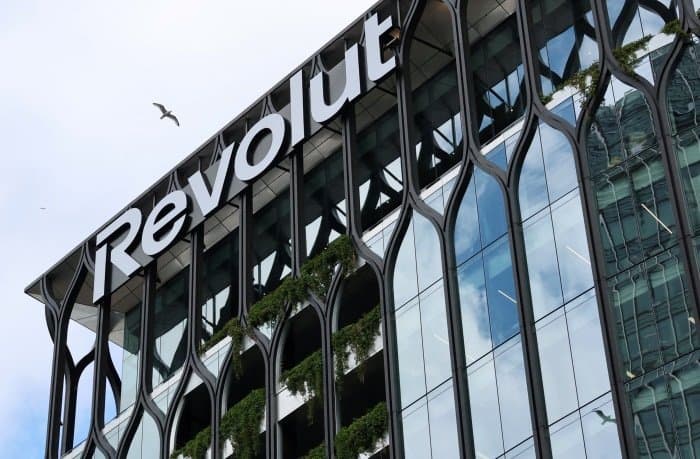 The Revolut global headquarters in Canary Wharf with a bird flying overhead.